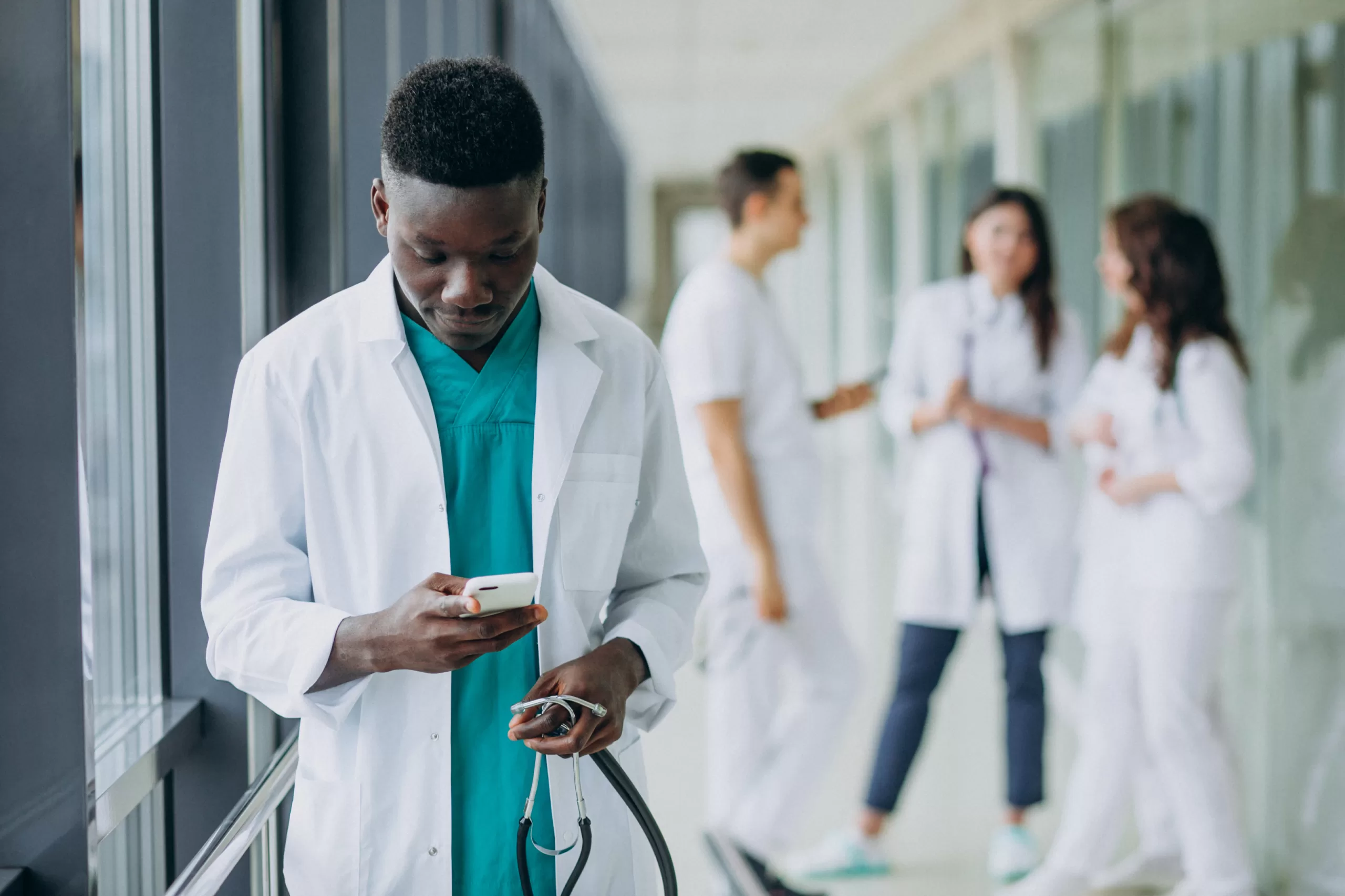 african american doctor man using smartphone corridor hospital scaled Leading Healthcare Consulting Across Togo